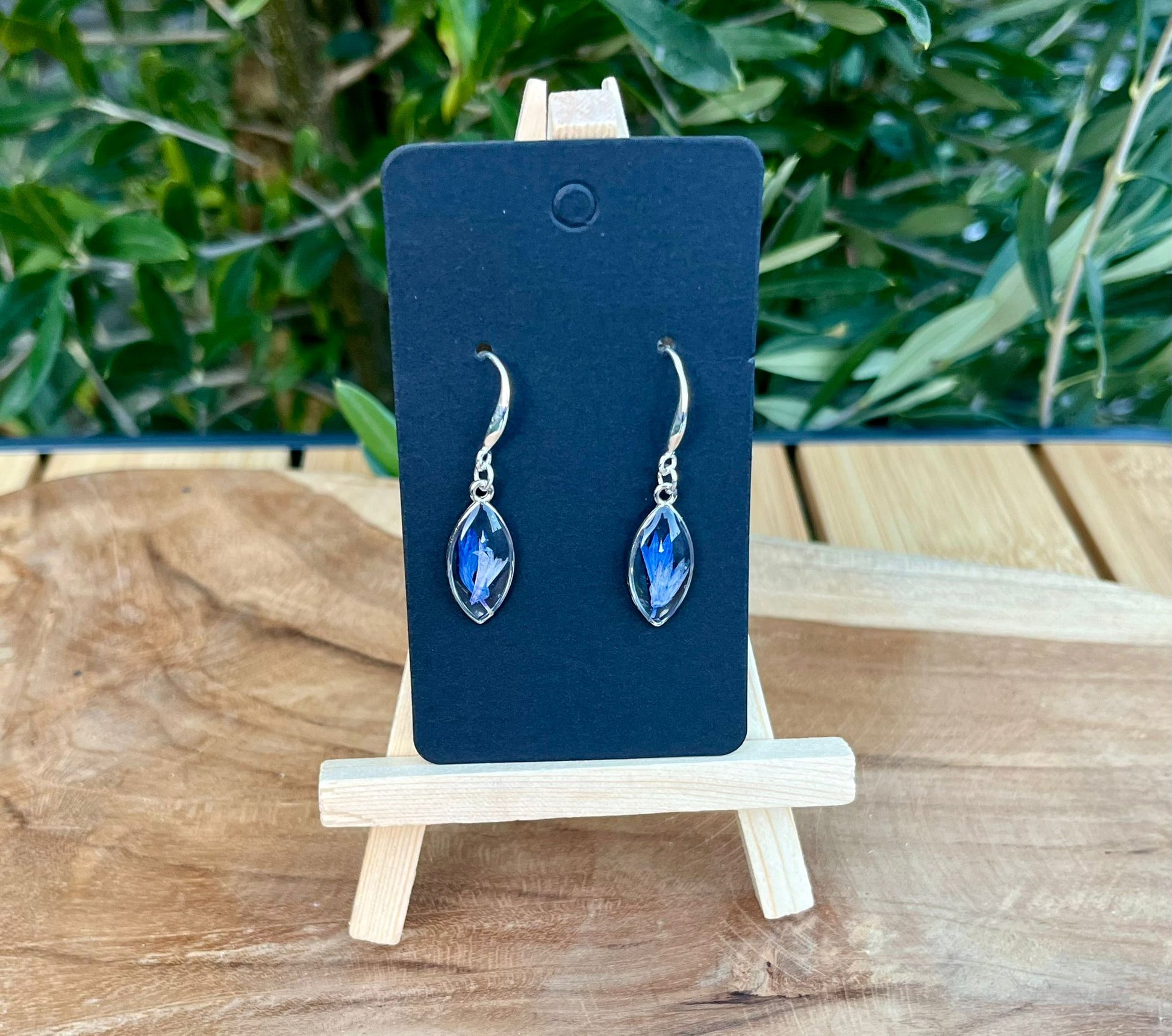 Handgemaakte zilveren oorbellen met echte gedroogde korenbloem, gegoten in UV resin. Licht en tijdloos design van Nova by Evi.